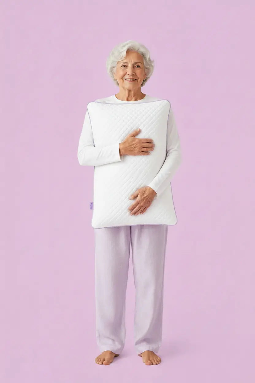 Older woman in pyjamas holding the SORA Adjust ergonomic pillow — lifestyle image on lavender background