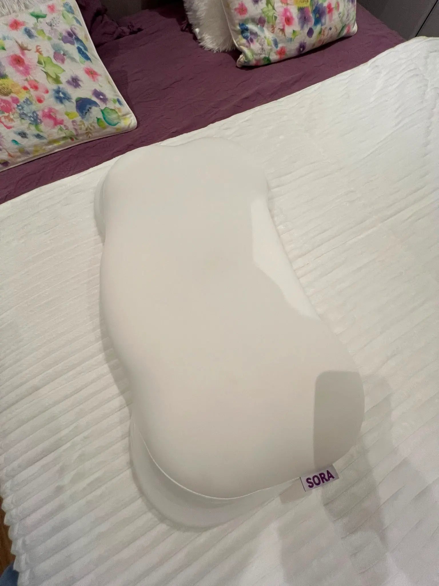Real customer photo of SORA Cloud ergonomic pillow on a bed — user-generated content showing bone-shaped memory foam pillow with SORA label in a home bedroom setting