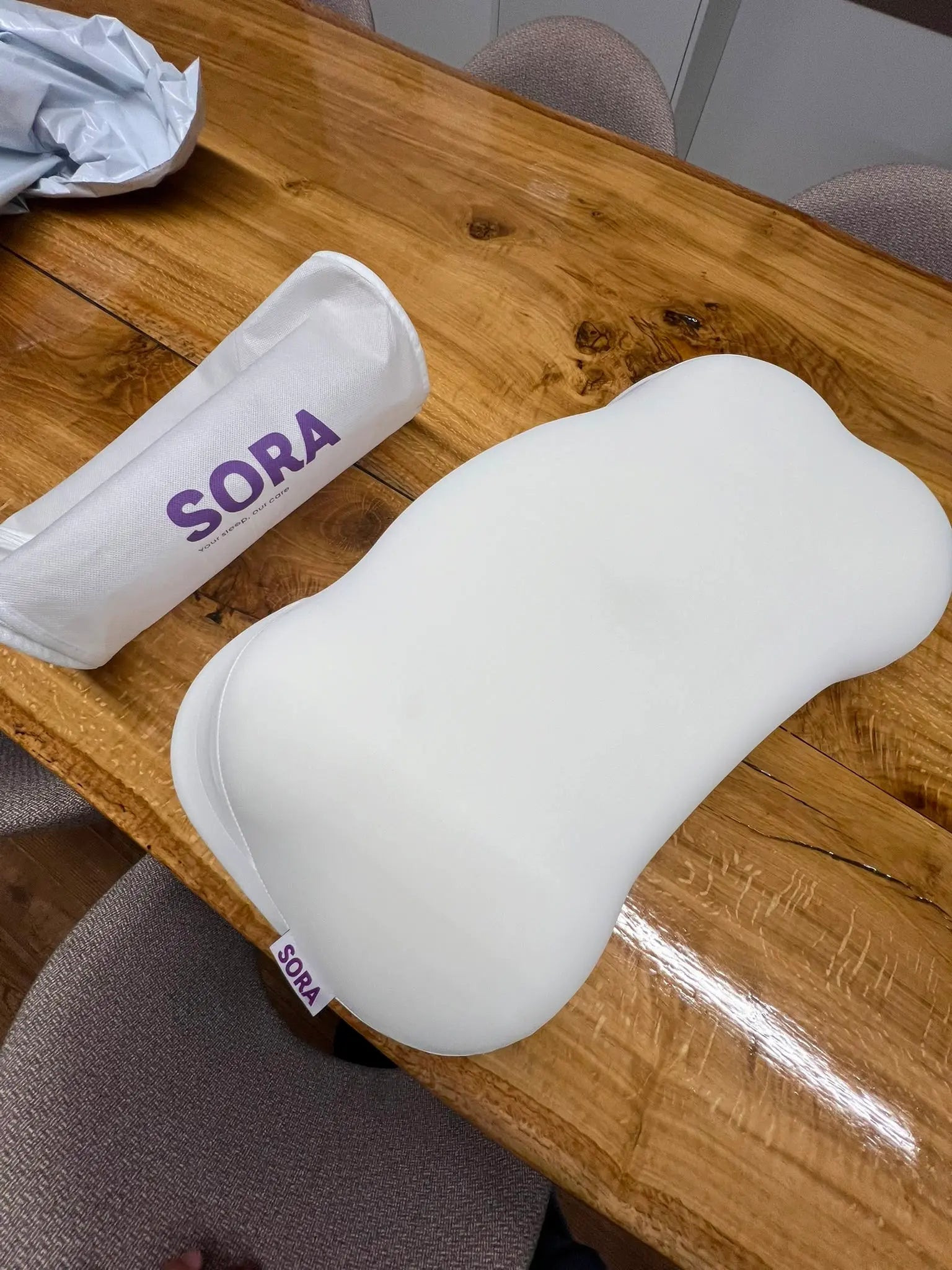 Real customer photo of SORA Cloud ergonomic pillow unboxed on a wooden table — user-generated content showing bone-shaped memory foam pillow alongside SORA branded packaging