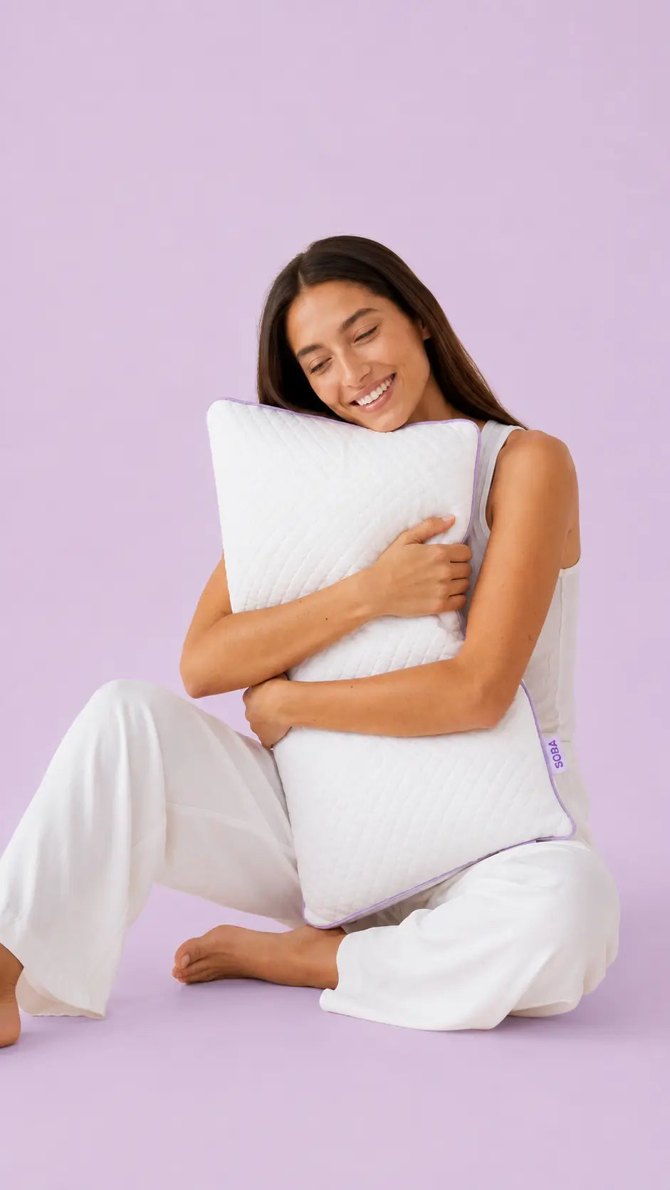 Young woman hugging the SORA Adjust ergonomic pillow — lifestyle image on lavender background