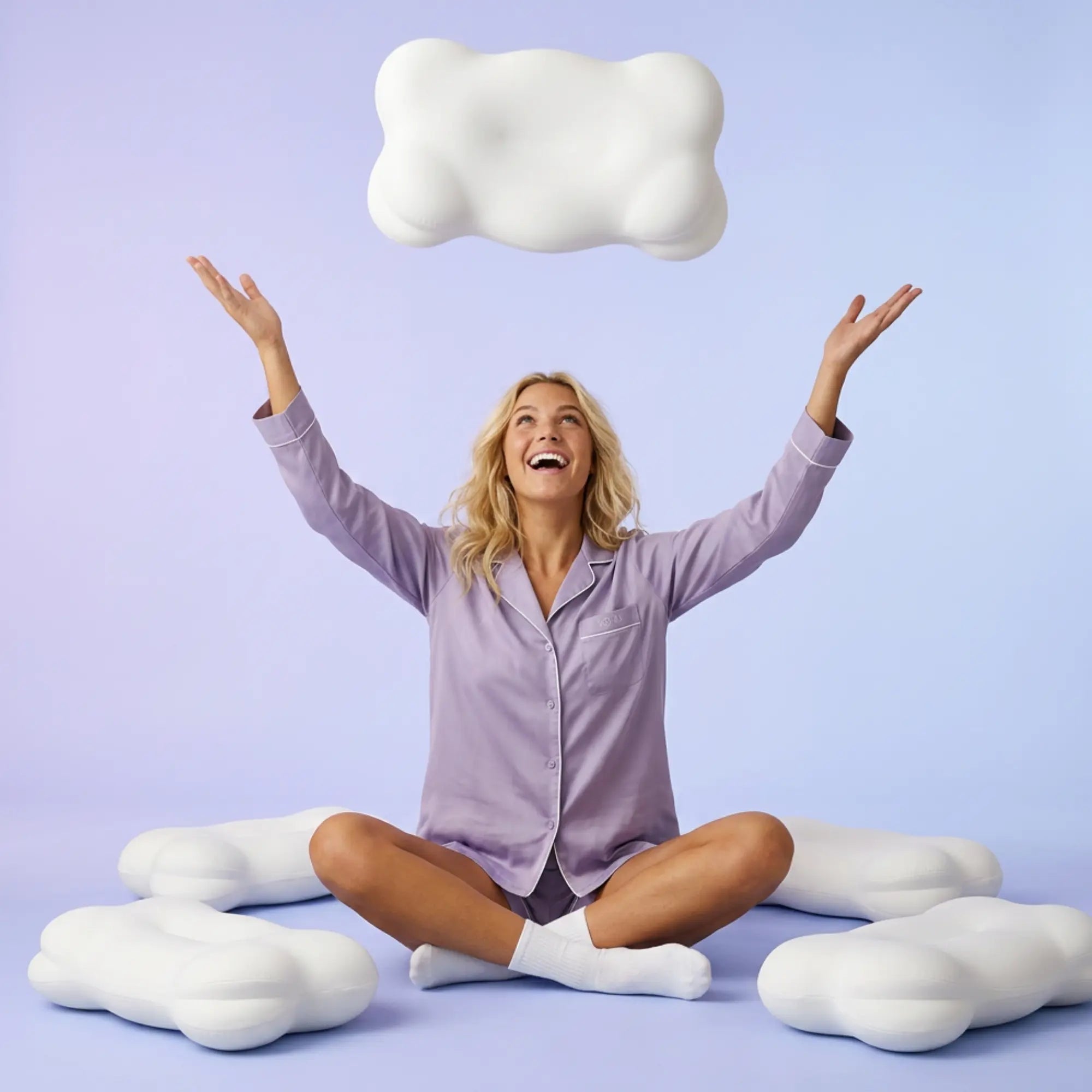 Woman in lavender pyjamas celebrating surrounded by SORA Cloud ergonomic pillows on purple background — lifestyle image showing joy and energy after a good night's sleep