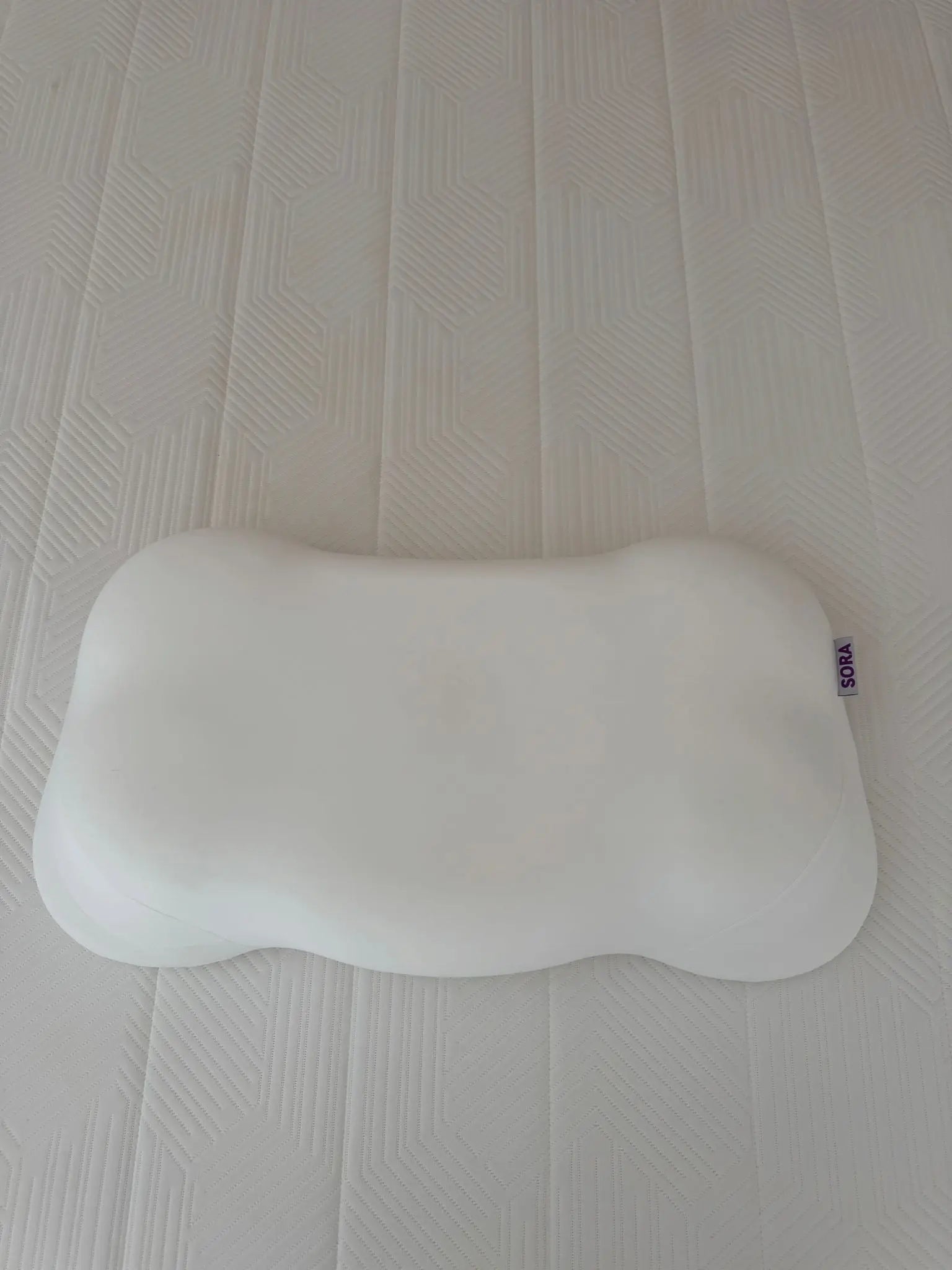 Real customer photo of SORA Cloud ergonomic pillow on a bed — user-generated content showing bone-shaped memory foam pillow with SORA label