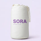 SORA Cloud ergonomic pillow shown from above on blush pink background with orange annotation arrows pointing to two zones. Soft Side for Back Sleepers at the top and Cervical Channel for Side Sleepers at the bottom