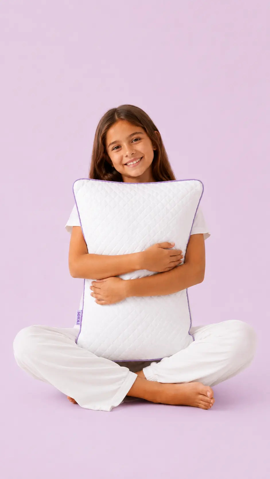 Young girl holding the SORA Adjust ergonomic pillow — lifestyle image on lavender background