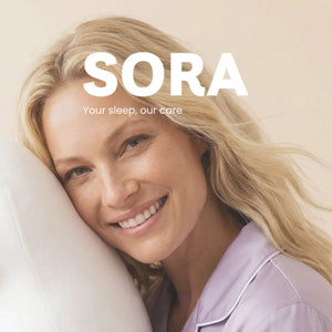 Woman resting on SORA ergonomic pillow smiling — wake up rested with SORA Cares sleep wellness brand