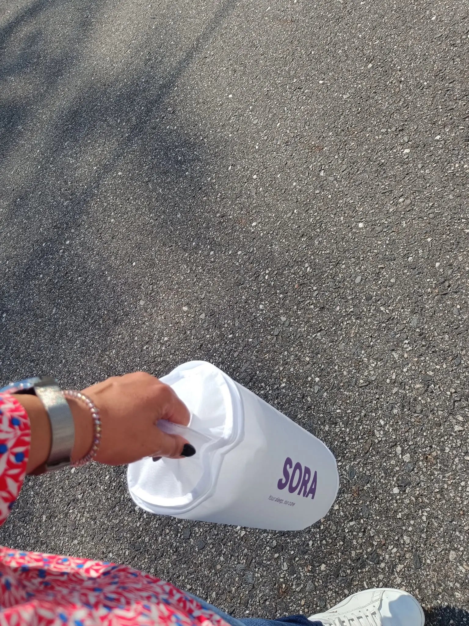 Woman holding SORA Cloud ergonomic pillow outdoors — lifestyle UGC photo showing the contoured memory foam design